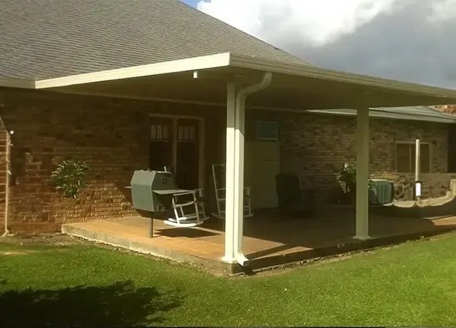 A patio cover with an open roof and a grill.