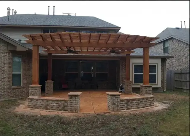 A large patio with brick walls and a wooden pergola.