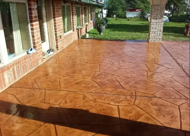 A patio with a brick wall and a large brown floor.