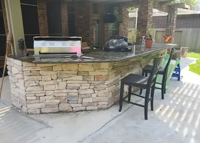 A stone bar with chairs and a grill