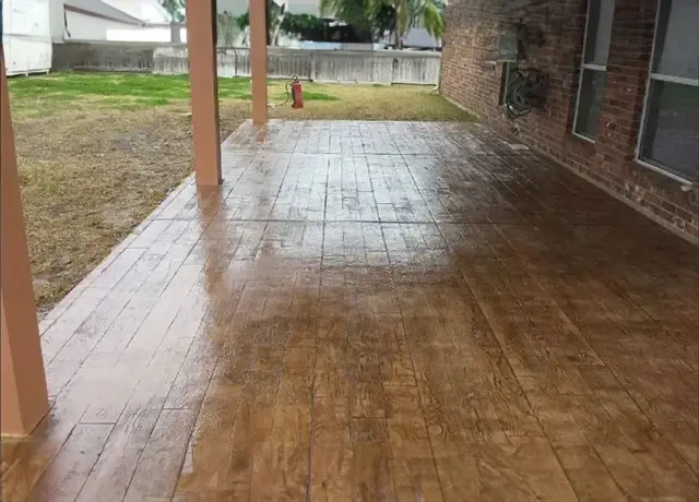 A patio with a wooden floor and a brick wall.