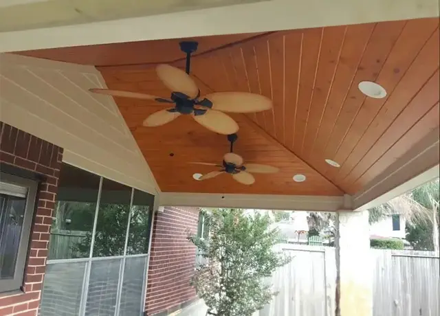 A ceiling fan is hanging from the rafters of an outdoor patio.