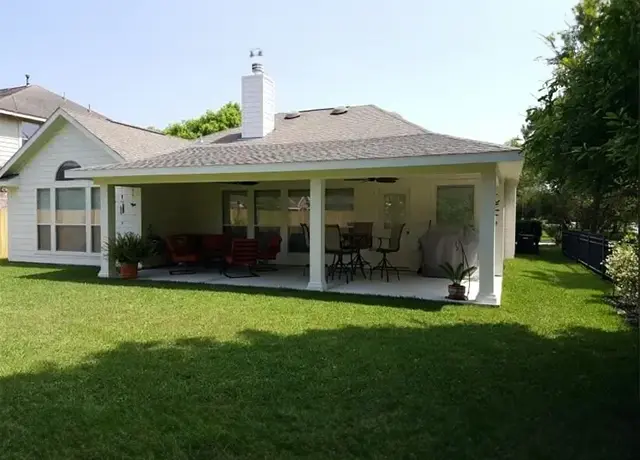 A large white covered patio with furniture in the yard.