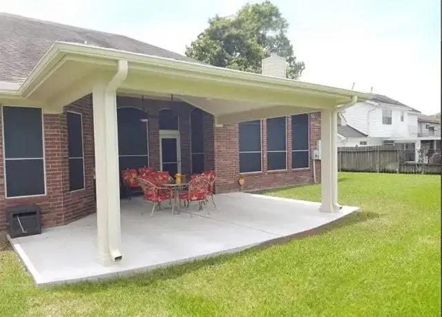 A patio with chairs and tables in the back yard.