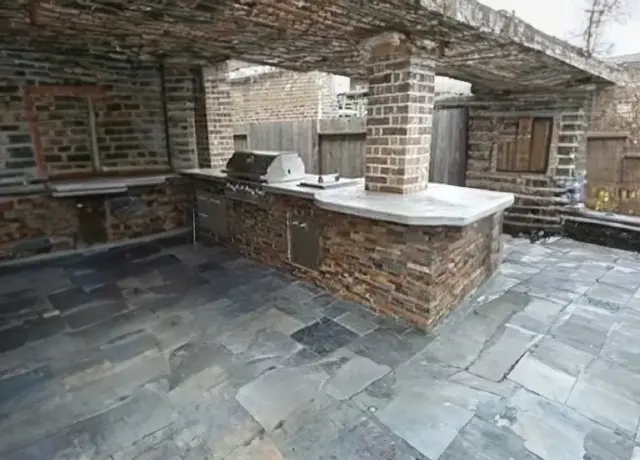 A brick outdoor kitchen with an oven and sink.