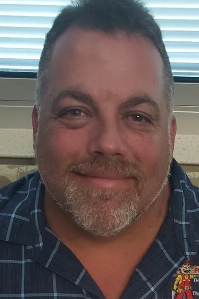 A man with a beard and mustache wearing a blue shirt.